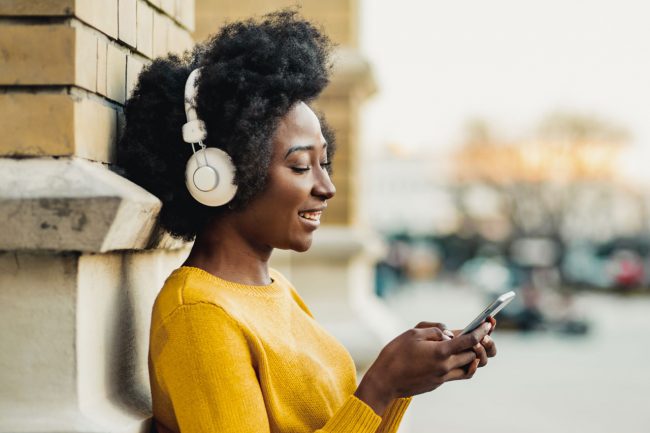 a women listening to headphones and typing on her phone